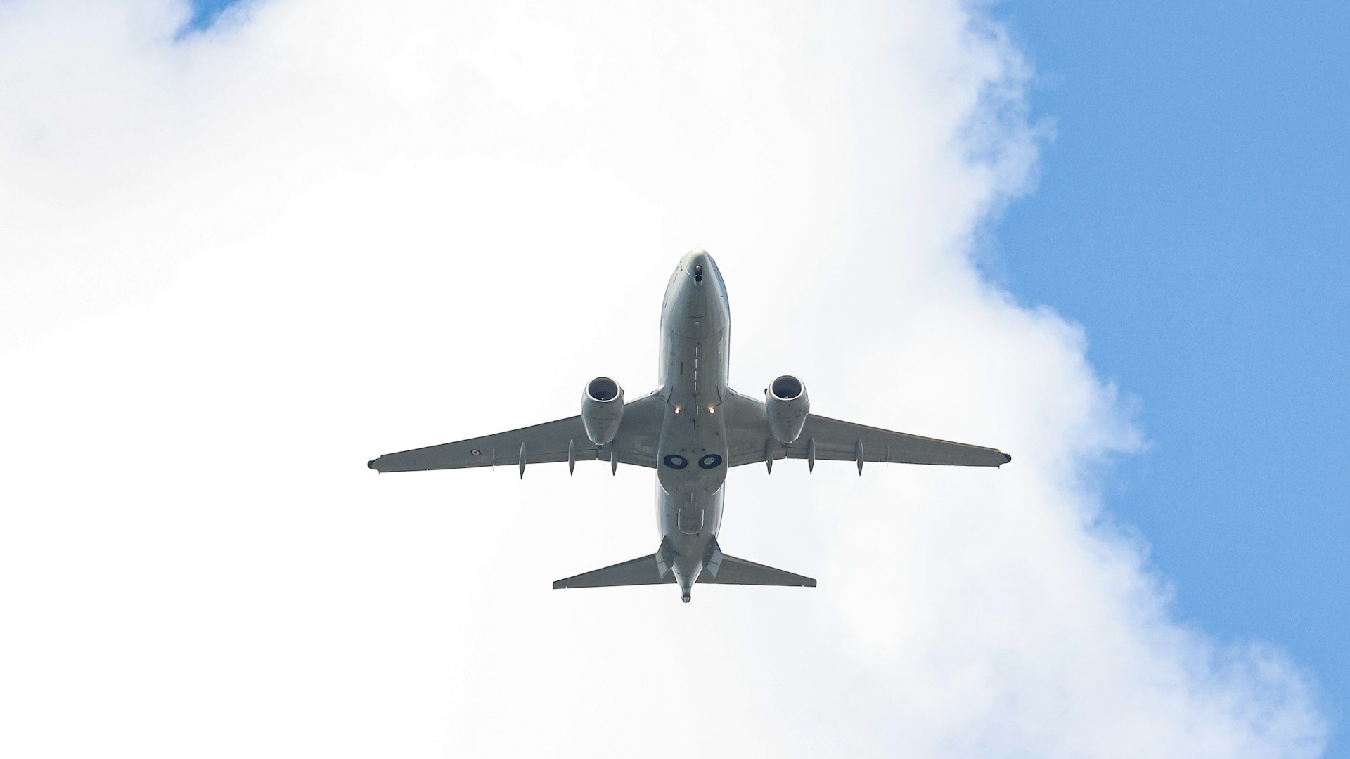 An airplane flying in the sky with a cloud in the background